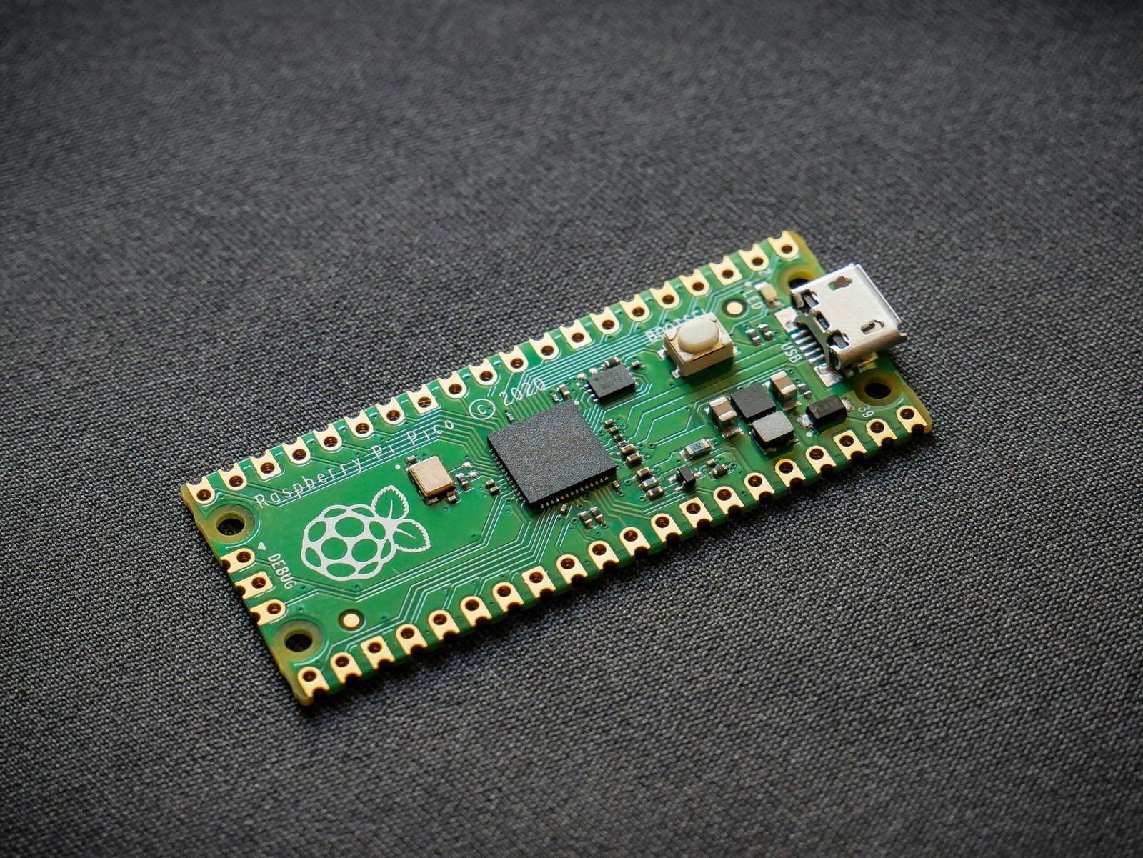 Microcontroller board with Raspberry Pi logo and USB port.
